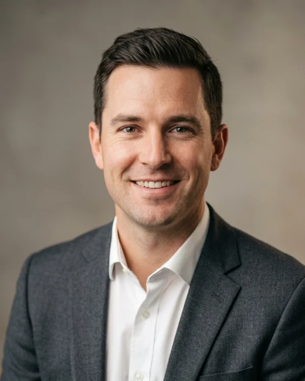 Blake Donovan, smiling, in a grey blazer and open-collar white shirt